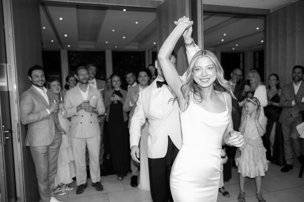 Braut tanzt ausgelassen auf der Hochzeitsparty, während Gäste im Hintergrund zusehen