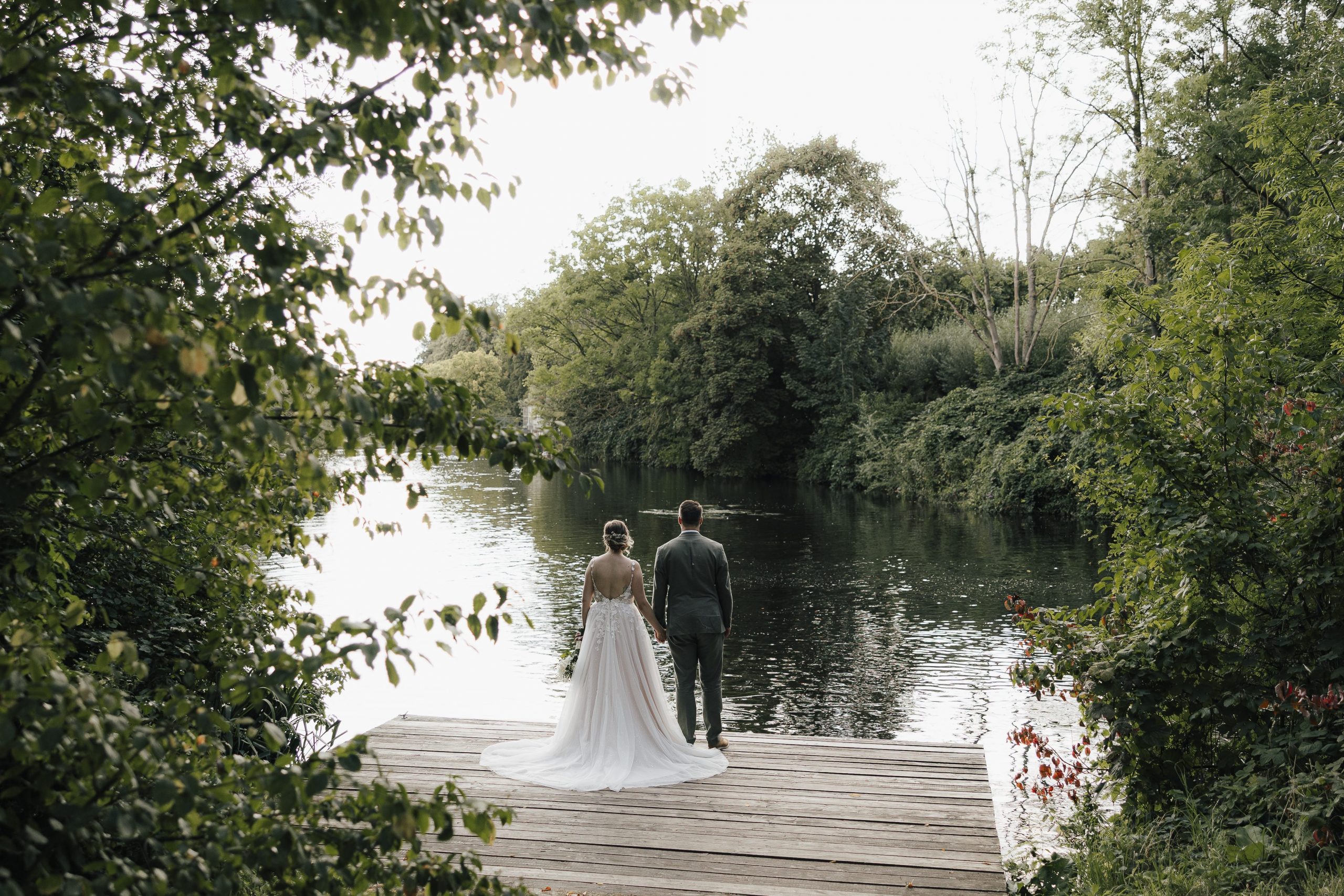 Ein Brautpaar schaut auf einen See.
