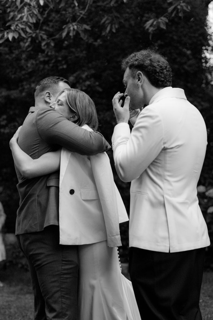 Braut umarmt ihren besten Freund. Bräutigam ist emotional berührt.